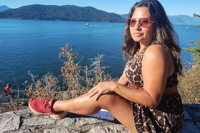 Una persona seduta su una sporgenza di pietra con vista su un lago e montagne sullo sfondo. 4