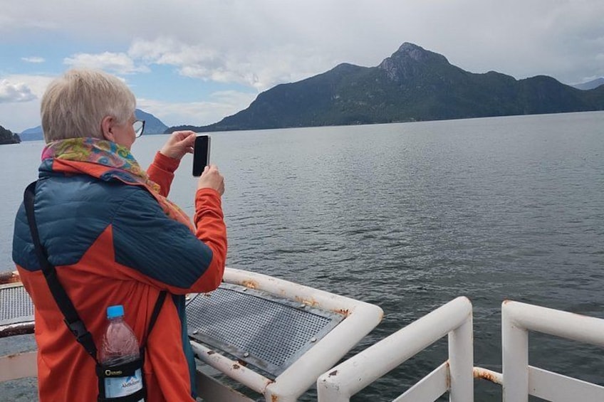 Una persona che fotografa un lago con montagne sullo sfondo. 5