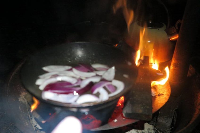 A pan with sliced onions over an open flame. 5