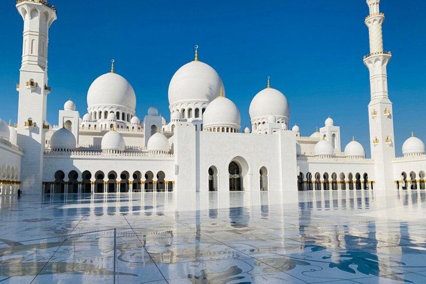 A white mosque with large domes and a tall minaret. 1