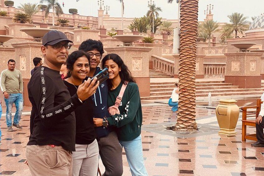 A group of people taking a selfie in a historic plaza with palm trees and a fountain. 5