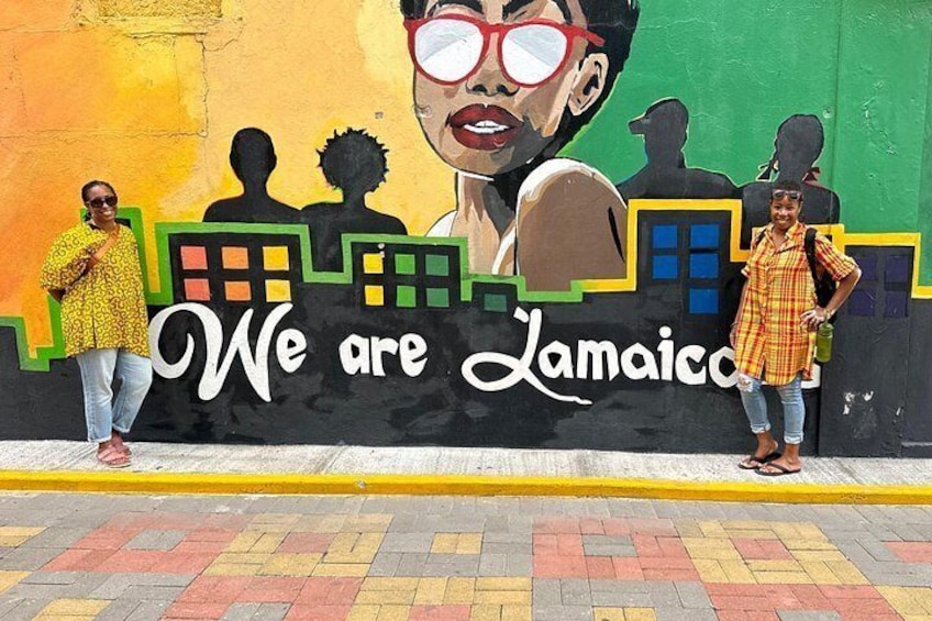 Une fresque murale avec le texte « Nous sommes la Jamaïque » et des silhouettes de personnes et de bâtiments. 5