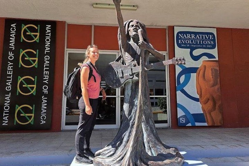 Een persoon staat naast een sculptuur voor de National Gallery of Jamaica. 1