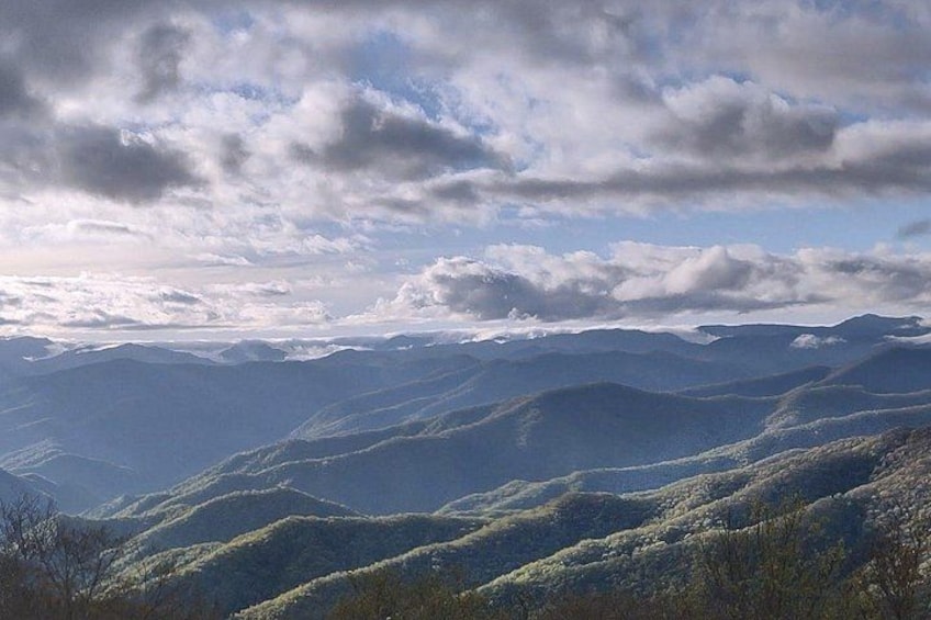 A mountainous landscape with rolling hills and a partly cloudy sky. 4
