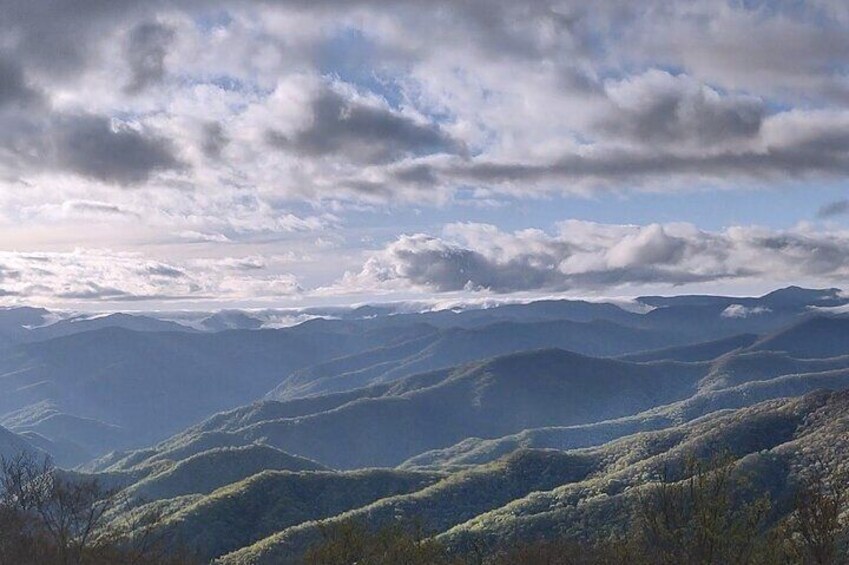 A mountainous landscape with rolling hills and a partly cloudy sky. 4