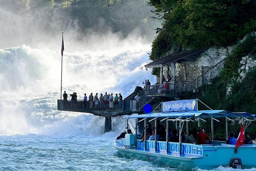 Ein Boot mit Passagieren, die einen Wasserfall beobachten. 1