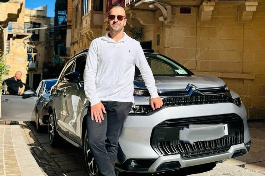 Un uomo in piedi accanto a un'auto argentata in una strada cittadina. 2