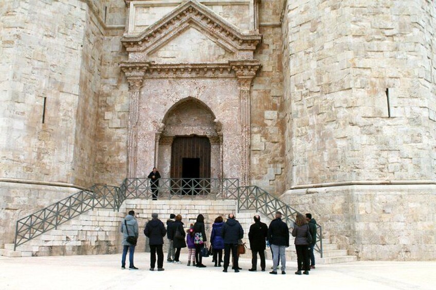 A group of people standing on a staircase in front of a stone building with an arched entrance. 2