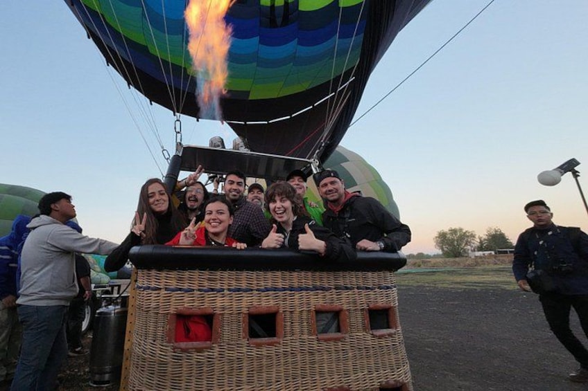 A hot air balloon with passengers, wicker basket, and a burner. 1