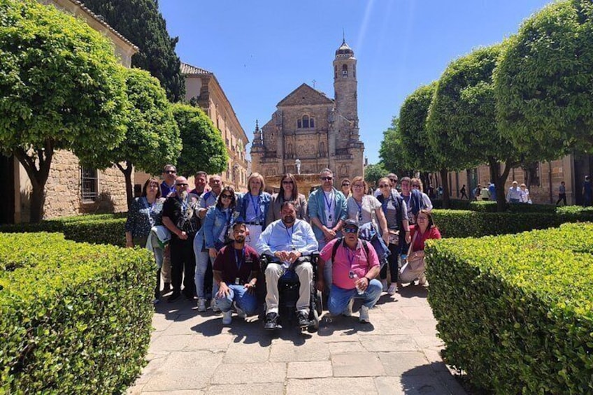 A group of people posing in a courtyard with a historic building in the background. 1