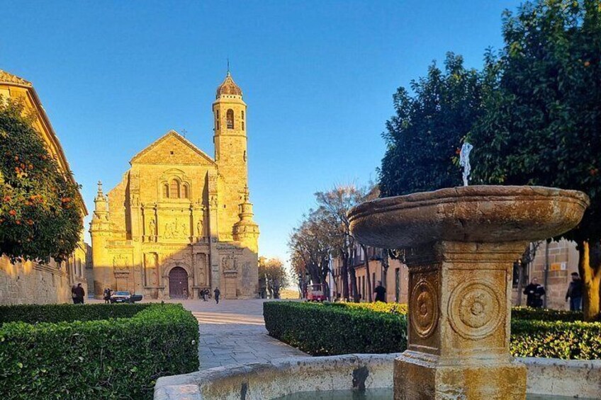 A historic church with a bell tower, a fountain, and well-maintained hedges. 3