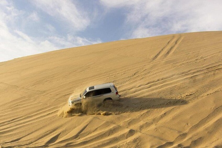 A white SUV driving through a sandy desert landscape. 2