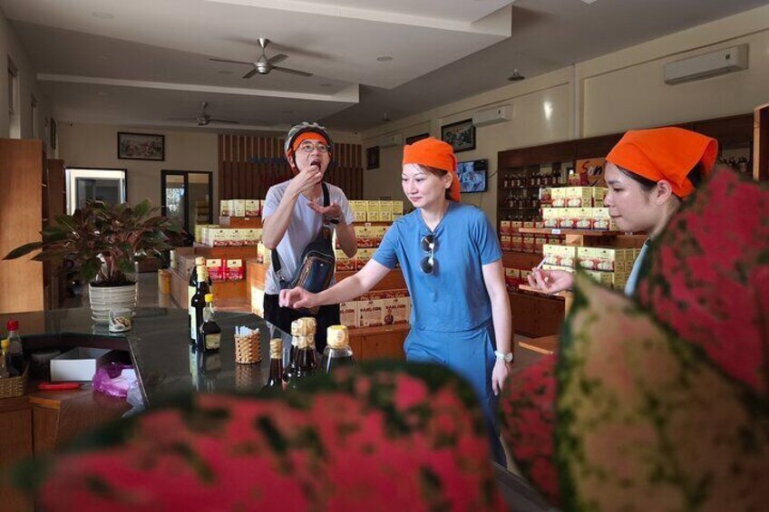 A person in a white shirt and orange cap standing at a counter with a laptop, another in blue scrubs and orange cap, and a third in orange cap. 5
