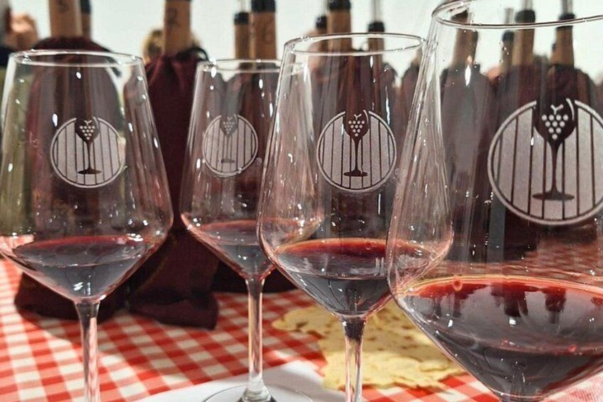 Wine glasses on a checkered tablecloth with a vineyard logo. 1