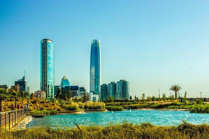 Une vue sur les toits d’une ville, avec des gratte-ciel modernes, une étendue d’eau et une zone herbeuse délimitée par une clôture. 5