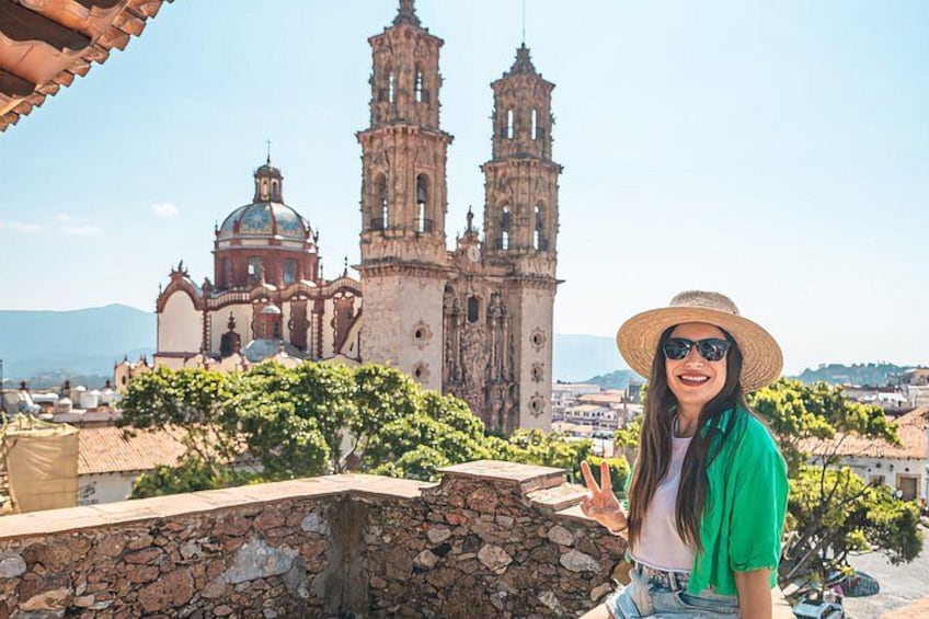 A person standing on a rooftop with a historic church and bell towers in the background. 1