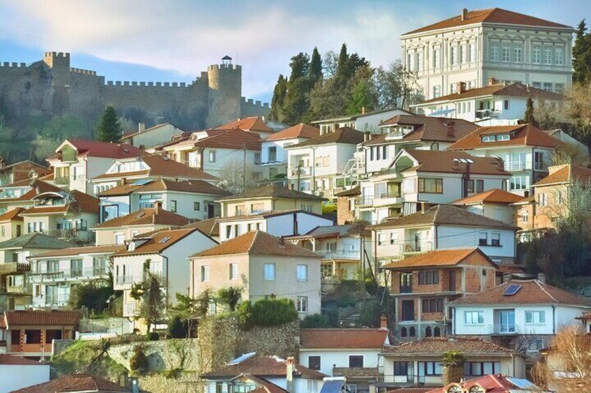 Un pueblo en una ladera con edificios históricos y un castillo al fondo. 4