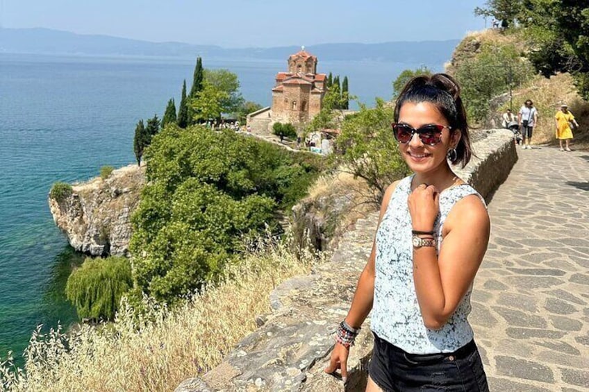 Una persona parada sobre un sendero de piedra, contemplando un cuerpo de agua con un edificio histórico al fondo. 3
