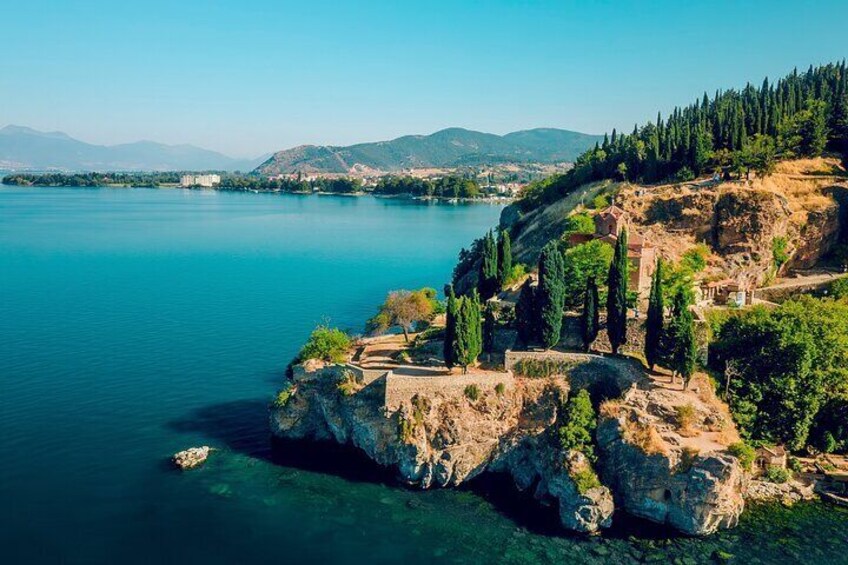 Un paisaje costero con un lago tranquilo, afloramientos rocosos y árboles dispersos. 3
