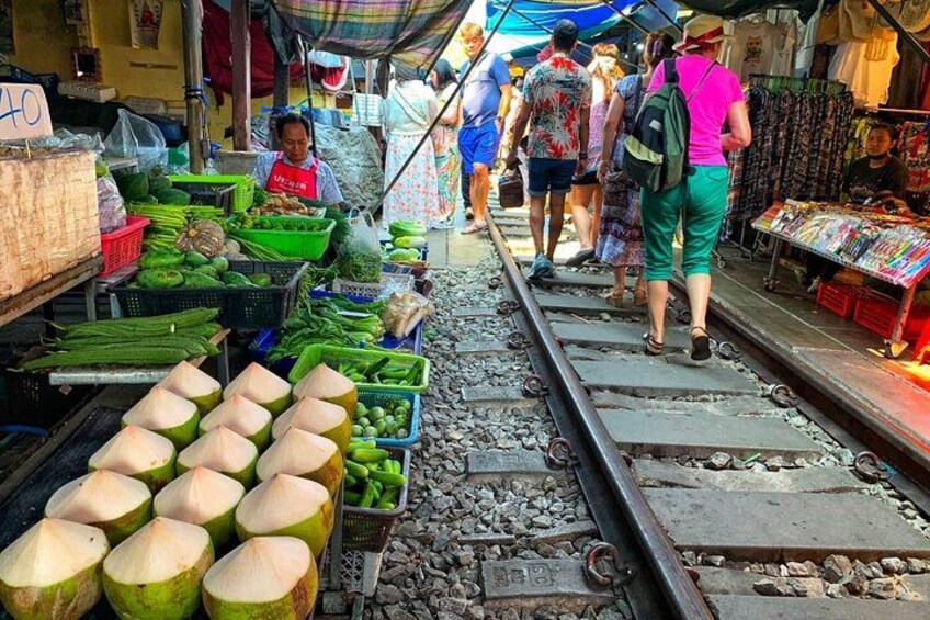 A market stall with green vegetables and coconuts on a railway track. 2