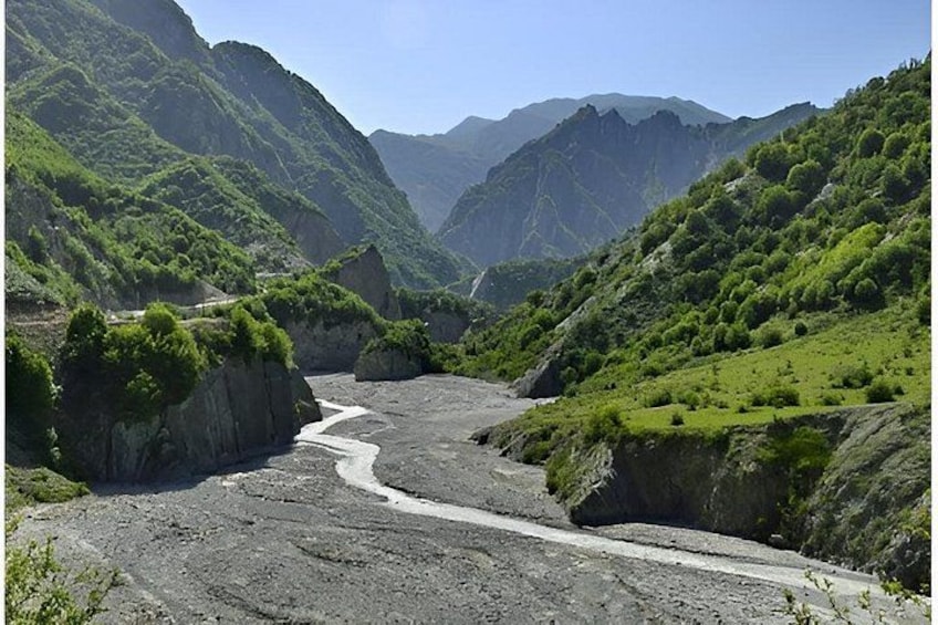 A river winding through a mountainous valley with lush greenery and rocky terrain. 3