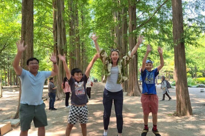A group of people in a park with tall trees and a dirt path. 1