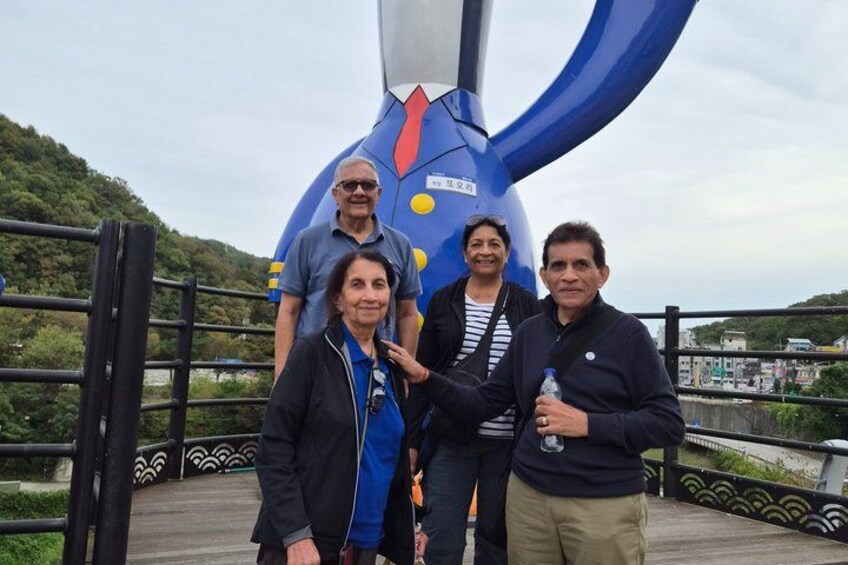 A group of people standing in front of a large blue sculpture with yellow and red accents. 4
