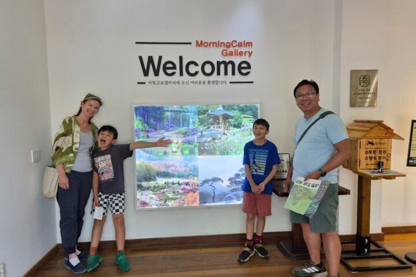 A family posing in front of a Welcome sign at the Morning Calm Gallery. 4