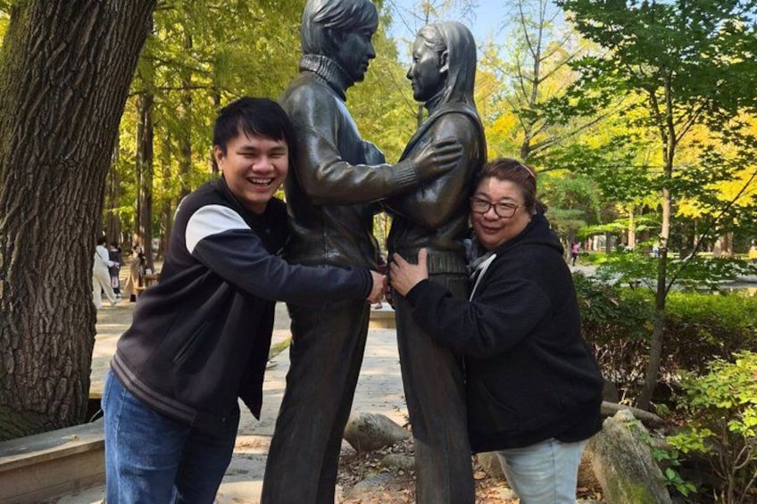 A bronze statue of a man and woman embracing in a park. 3
