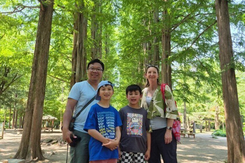 A family of four in a forested area with tall trees and a clear sky. 3