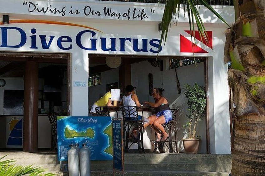 A DiveGurus dive shop with two people sitting at a table outside. 2