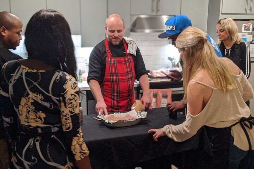 A group of people around a table with food items, possibly preparing or serving food. 1