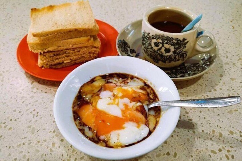 Un tazón de sopa con un huevo escalfado, tostadas y una taza de café sobre una mesa. 3