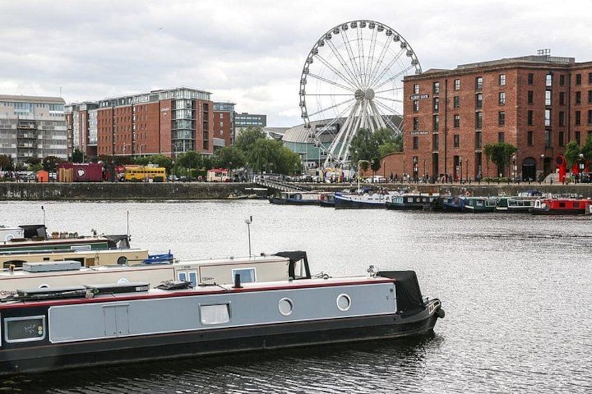 A river with a boat, a Ferris wheel, and buildings in the background. 2