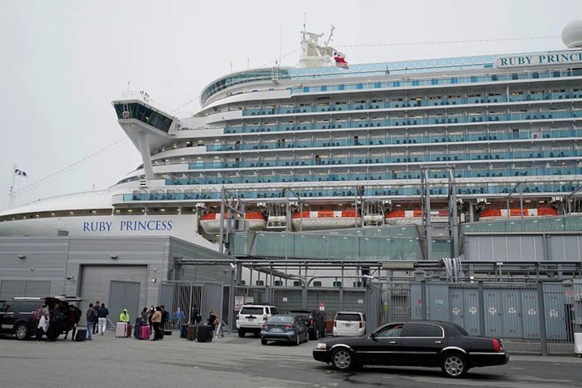 A large cruise ship named Ruby Princess docked at a port with people and vehicles around. 5