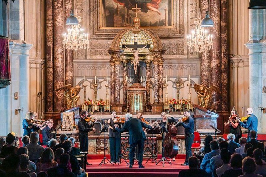 A classical music concert in a grand hall with ornate decorations and a large audience. 3