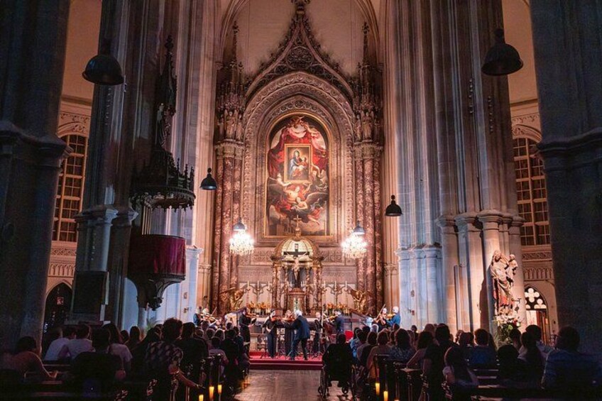 An ornate church interior with a large altar, pews, and a crowd of people. 3