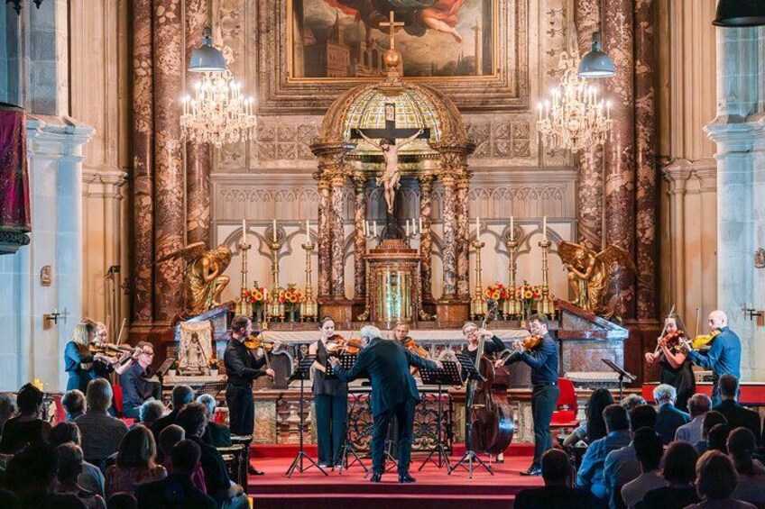 A classical music concert in a grand hall with ornate decorations and a large audience. 4