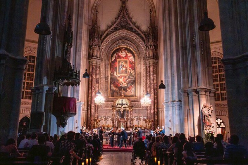 An ornate church interior with a large altar, pews, and a crowd of people. 3