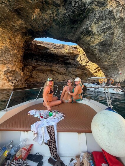 Three people on a boat with a rocky cave in the background. 5