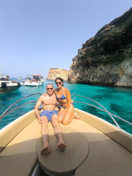 Un couple est à bord d’un bateau, avec une eau turquoise cristalline et des falaises rocheuses en arrière-plan. 4
