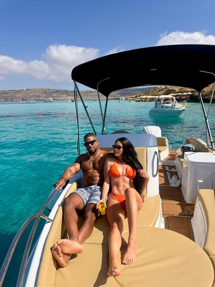 Deux personnes se trouvent sur un bateau, avec une mer d’un bleu limpide et une côte rocheuse en arrière-plan. 1
