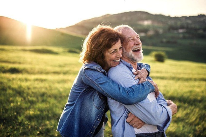 A couple embracing in a grassy field with a sunset in the background. 3