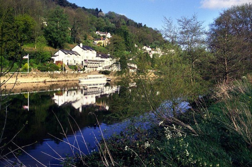 A calm river with a reflection of buildings, surrounded by greenery and trees. 5
