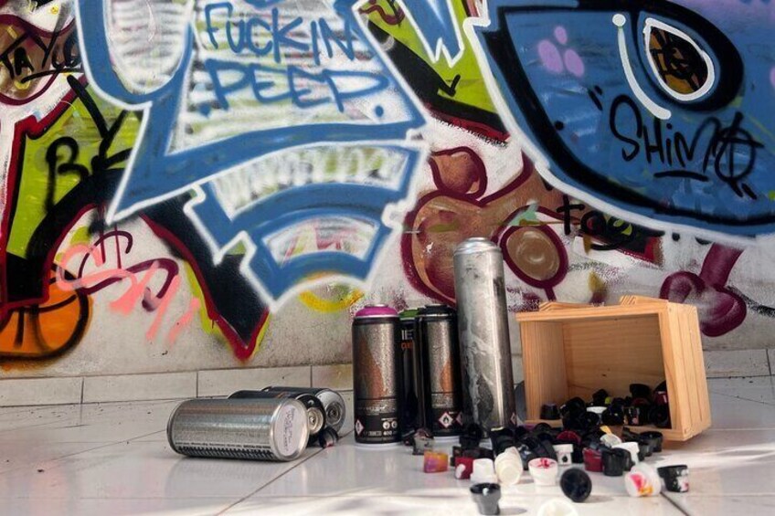 Una pared cubierta de grafitis con latas y zapatos dispersos en el suelo. 1