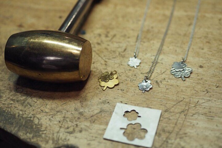 En metalgenstand, måske et værktøj, og flere smykker med blomstermotiver på en træoverflade. 3
