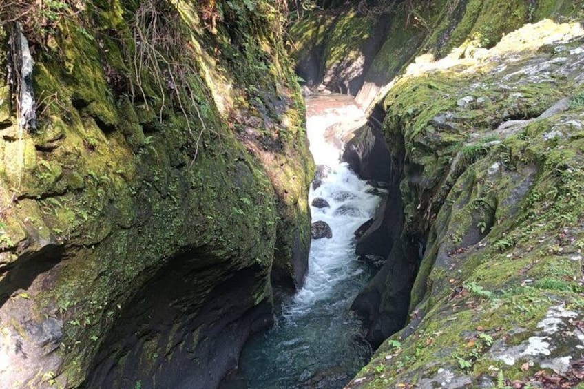 Un canyon étroit, traversé par une rivière, avec des rochers couverts de mousse et la lumière du soleil qui filtre à travers. 3