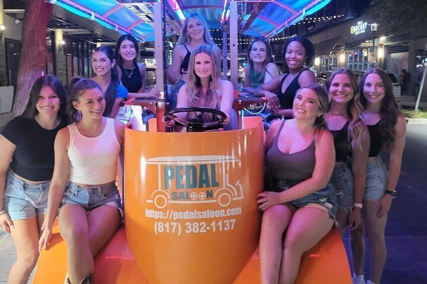 Un grupo de personas en un vehículo de pedales con un letrero que dice 'PEDAL SALON'. 1