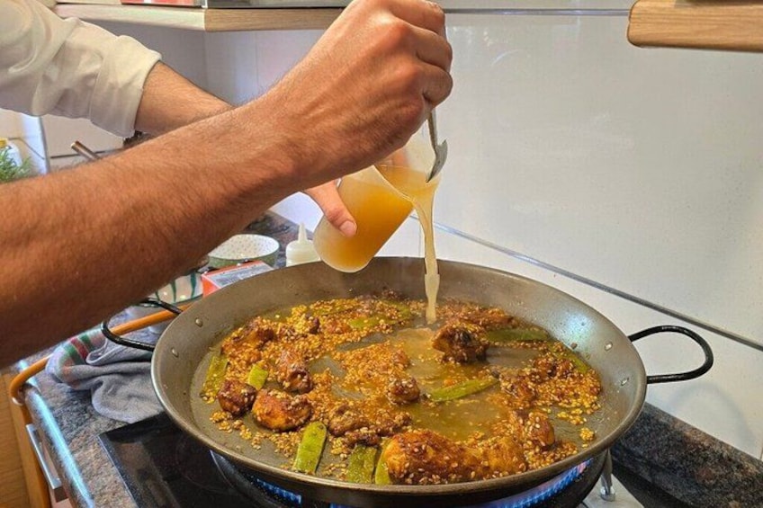 A person cooking in a pan with meat and vegetables on a stove. 5