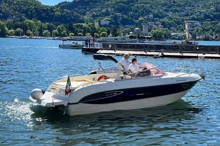 A motorboat on calm water with a dock and buildings in the background. 4